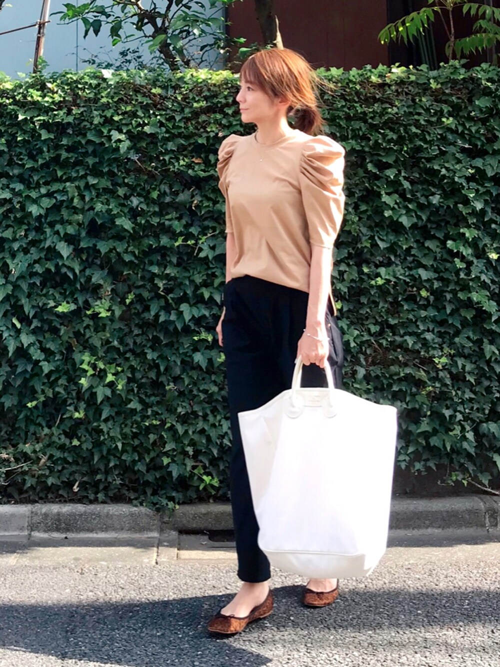 ベージュ系のTシャツ/カットソー、ホワイト系のトートバッグ、ブラック系のパンツを着用したレディースの夏コーディネートの2枚目の写真