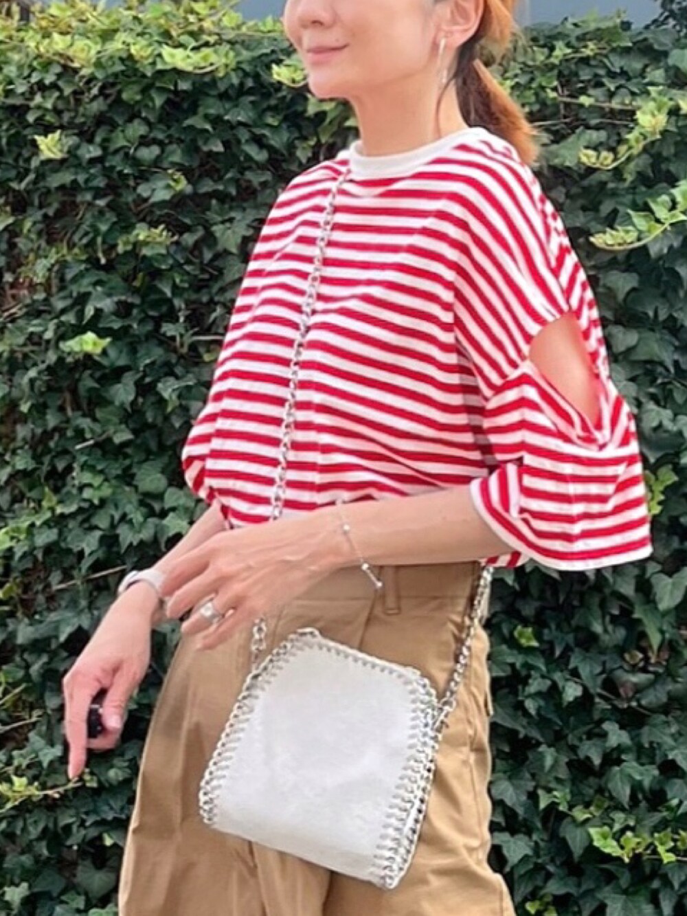 レッド系のTシャツ/カットソー、イエロー系のチノパンツ、ホワイト系のショルダーバッグを着用したレディースの夏コーディネートの3枚目の写真