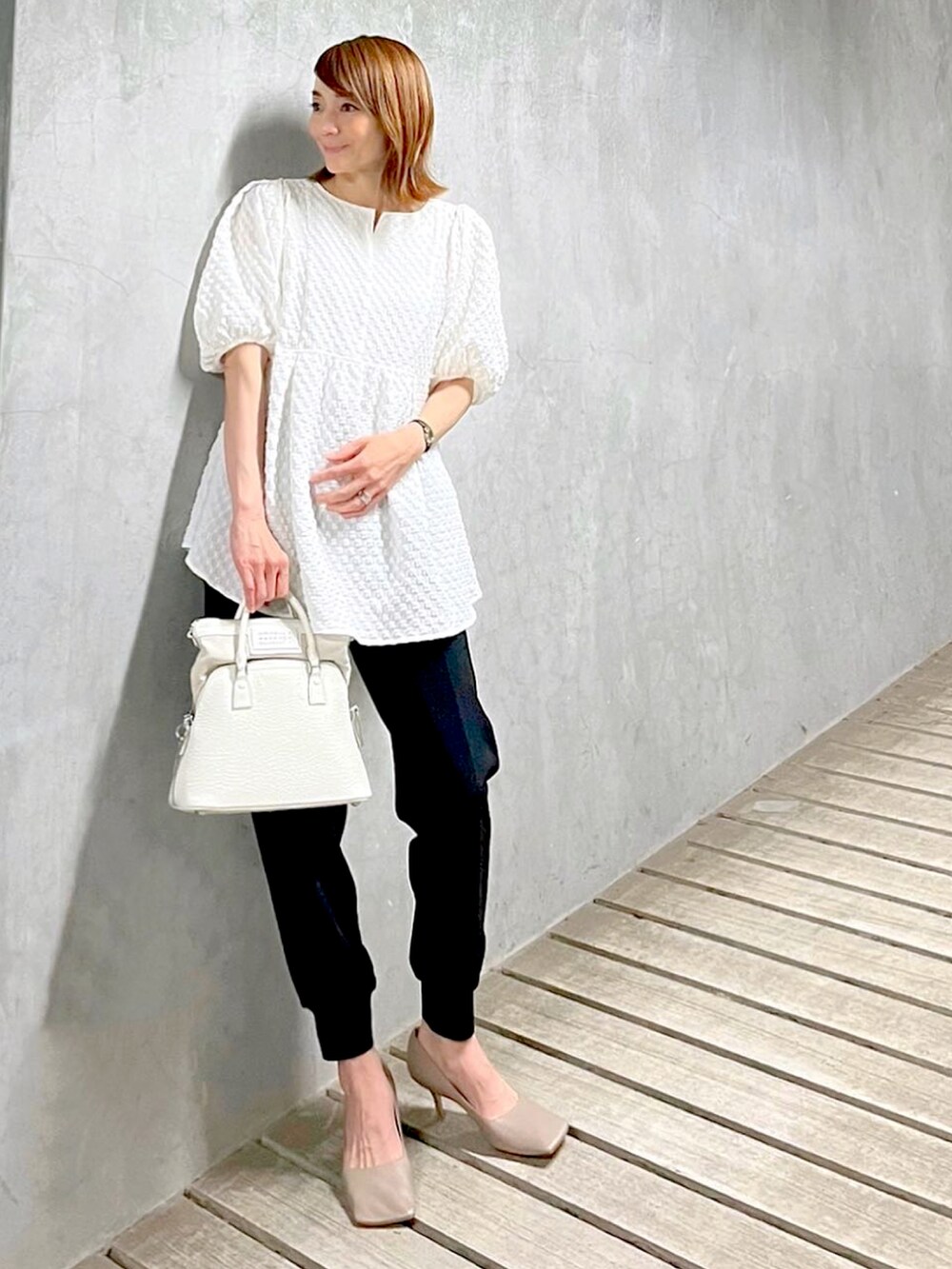 ホワイト系のハンドバッグ、グレー系のパンプス、ブラック系のその他パンツを着用したレディースの春コーディネートの2枚目の写真