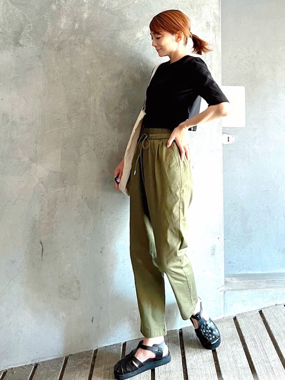 ブラック系のTシャツ/カットソー、ブラック系のサンダル、ホワイト系のトートバッグを着用したレディースの秋コーディネートの2枚目の写真