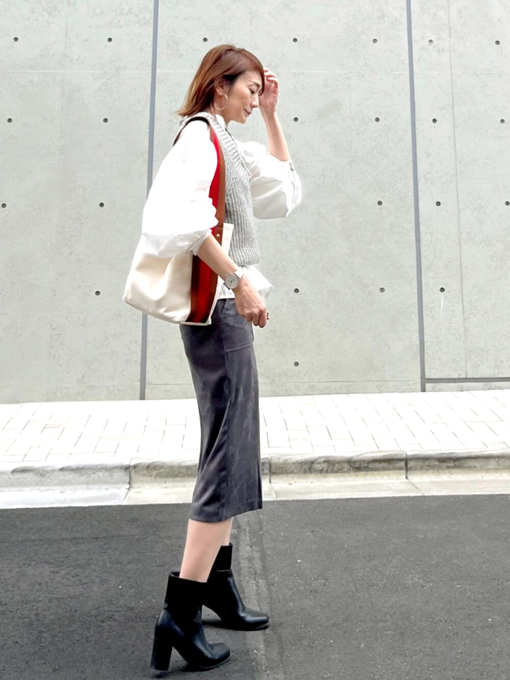 グレー系のスカート、ホワイト系のシャツ/ブラウス、ブラウン系のショルダーバッグを着用したレディースの秋コーディネートの2枚目の写真