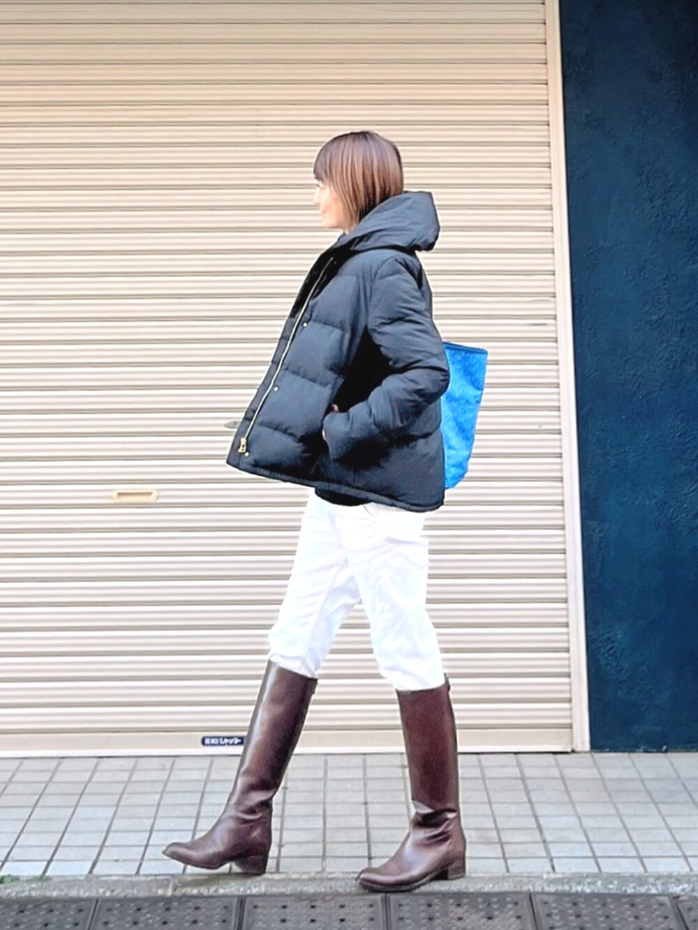 ブルー系のトートバッグ、ブラック系のダウンジャケット/コート、ブラウン系のブーツを着用したレディースの冬コーディネートの3枚目の写真