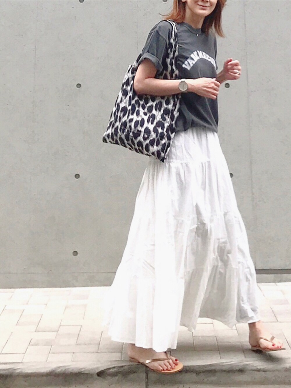 ホワイト系のスカート、グレー系のトートバッグ、ゴールド系のサンダルを着用したレディースの春コーディネートの3枚目の写真