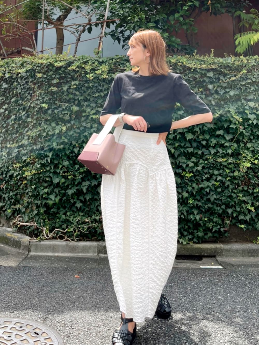 ブラック系のTシャツ/カットソー、ホワイト系のスカート、パープル系のバッグを着用したレディースの秋コーディネートの2枚目の写真