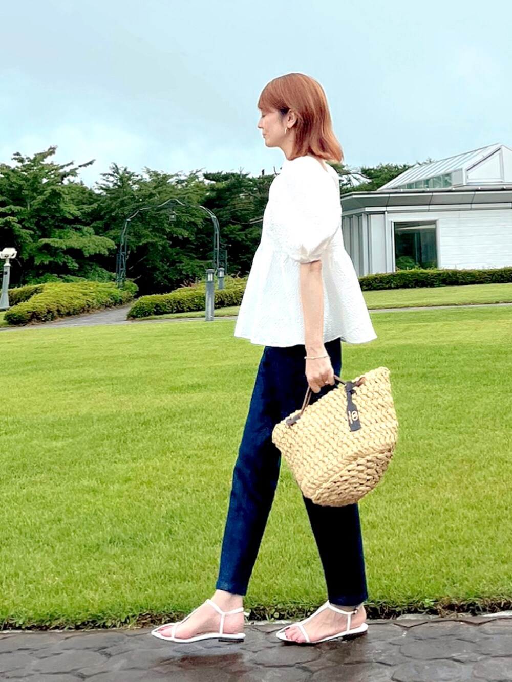 ホワイト系のシャツ/ブラウス、ブルー系のデニムパンツ、ベージュ系のハンドバッグを着用したレディースの夏コーディネートの3枚目の写真