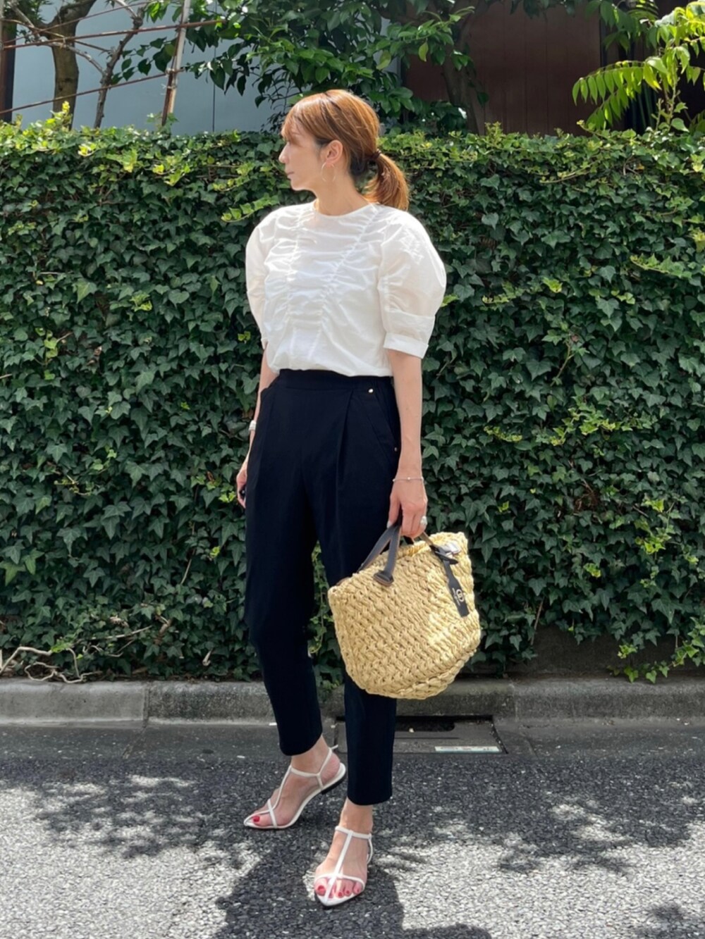 ホワイト系のシャツ/ブラウス、ベージュ系のハンドバッグ、ホワイト系のサンダルを着用したレディースの夏コーディネートの2枚目の写真