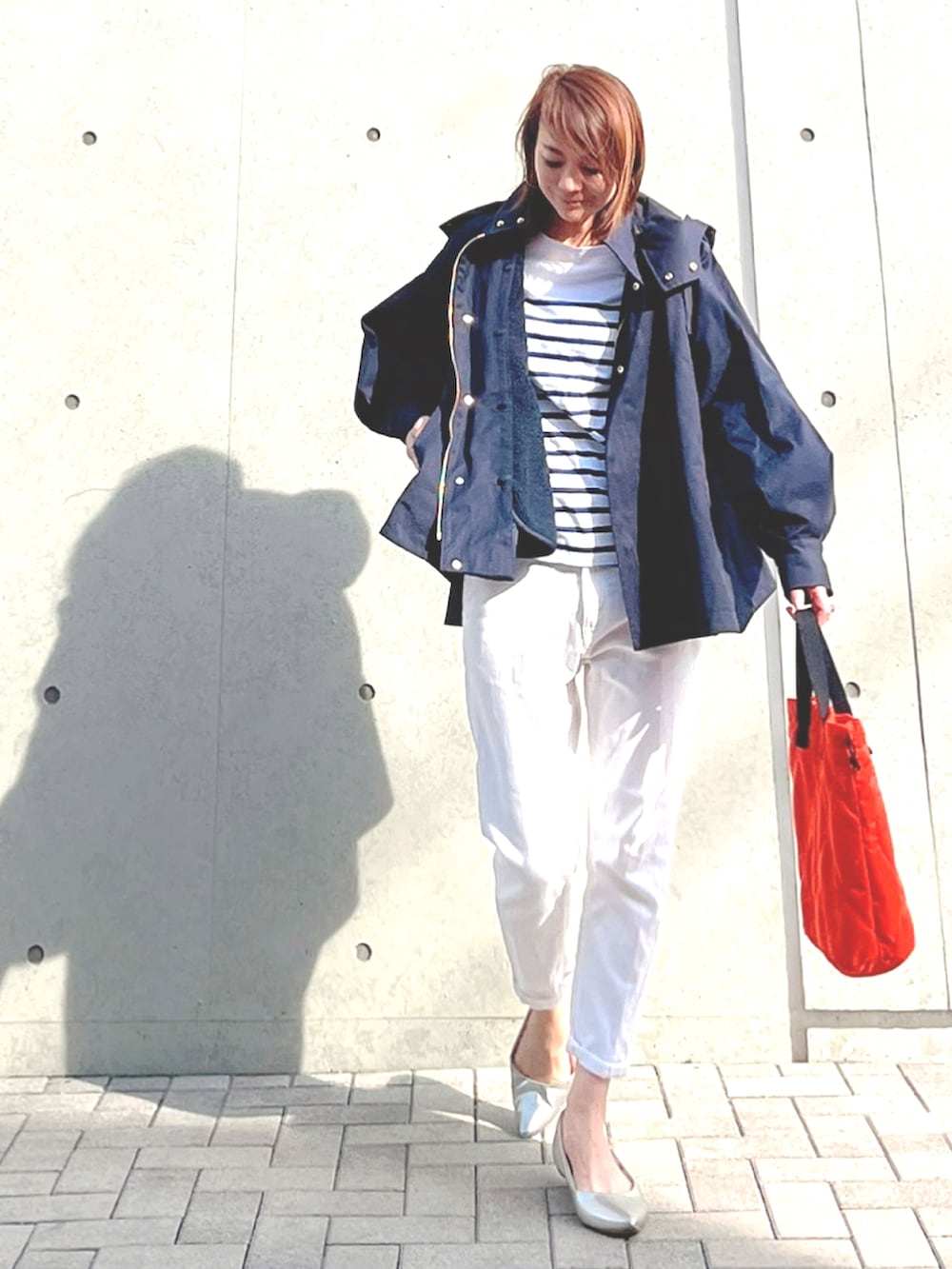 ブルー系のマウンテンパーカー、ホワイト系のTシャツ/カットソー、オレンジ系のトートバッグを着用したレディースの春コーディネートの3枚目の写真