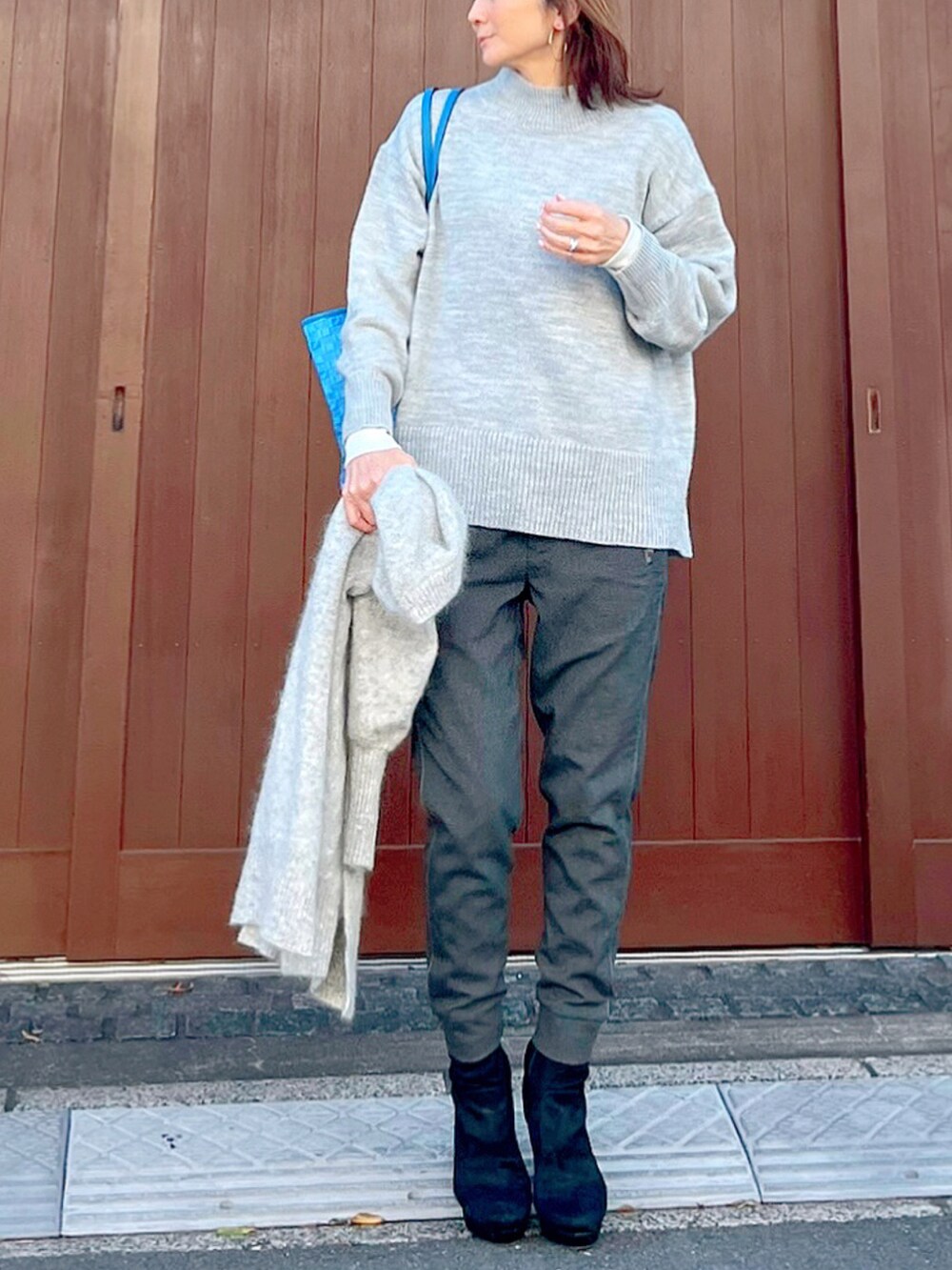 グレー系のニット/セーター、ブルー系のトートバッグ、ブラック系のブーツを着用したレディースの冬コーディネートの2枚目の写真
