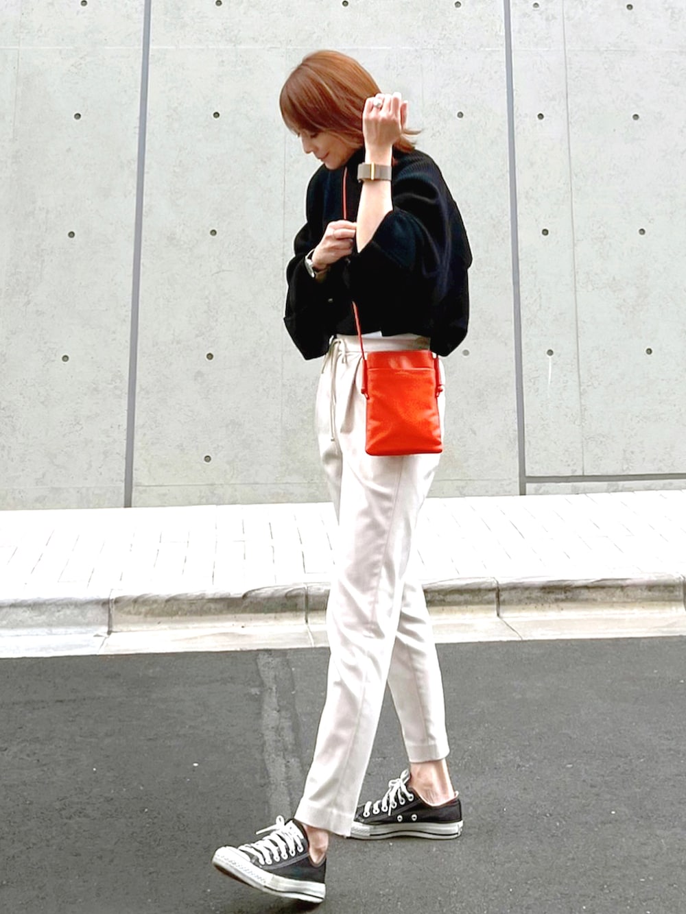 オレンジ系のショルダーバッグ、ブラック系のニット/セーター、ホワイト系のその他パンツを着用したレディースの秋コーディネートの2枚目の写真