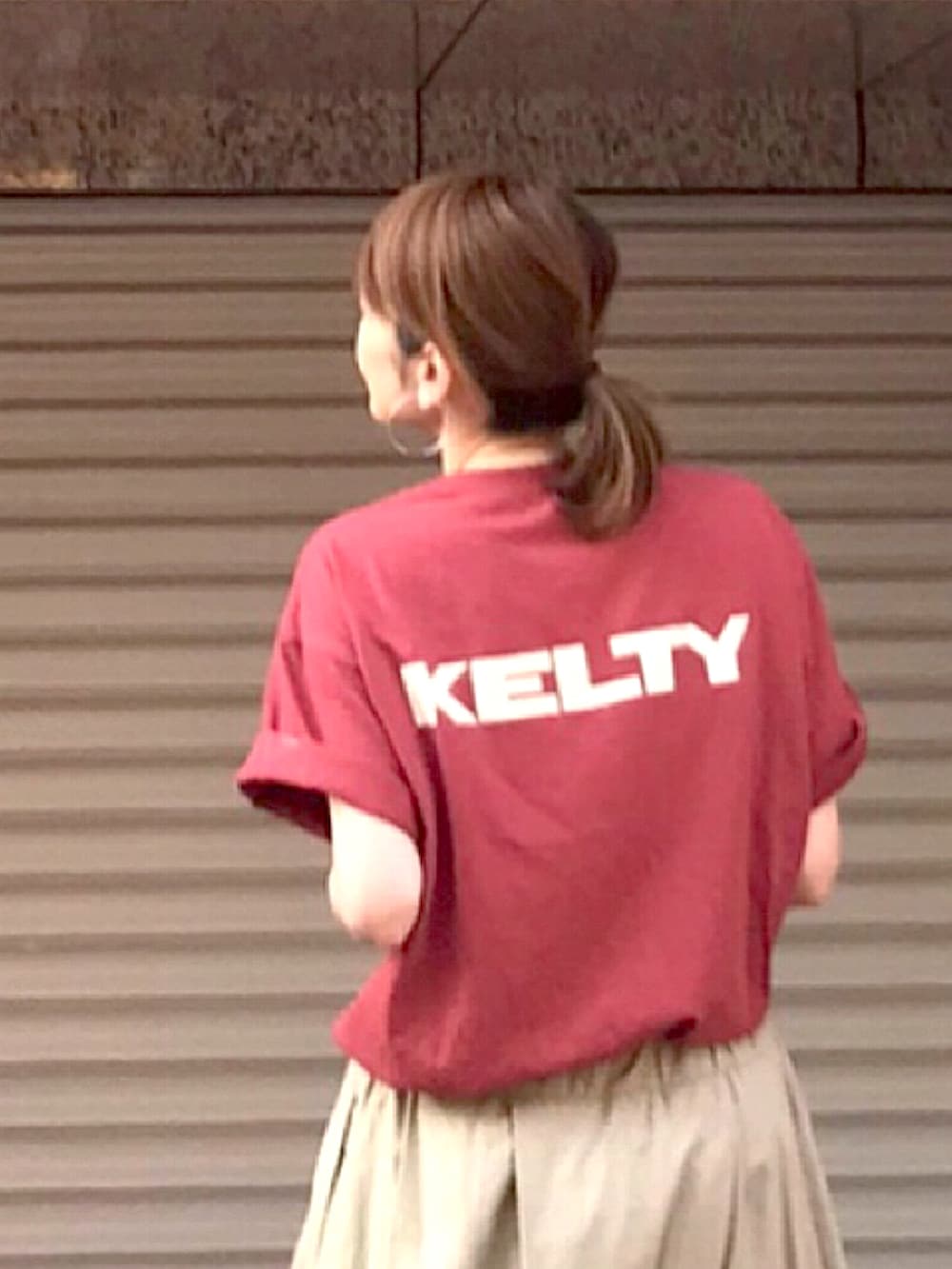 レッド系のTシャツ/カットソー、ベージュ系のスカート、ホワイト系のショルダーバッグを着用したレディースの夏コーディネートの2枚目の写真