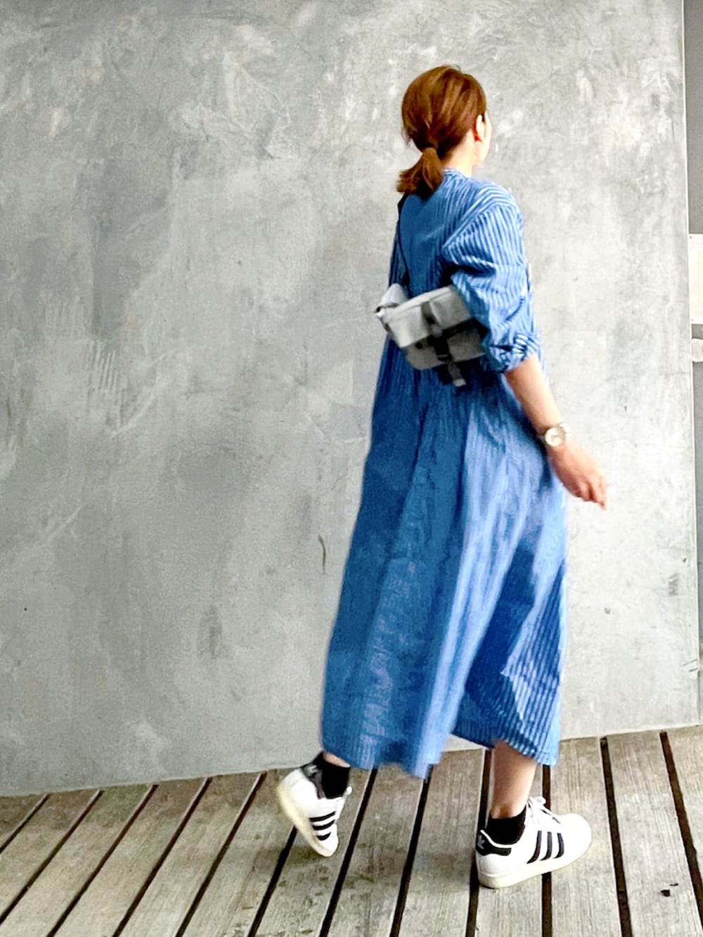 ブルー系のワンピース、グレー系のバッグ、ホワイト系のスニーカーを着用したレディースの秋コーディネートの2枚目の写真