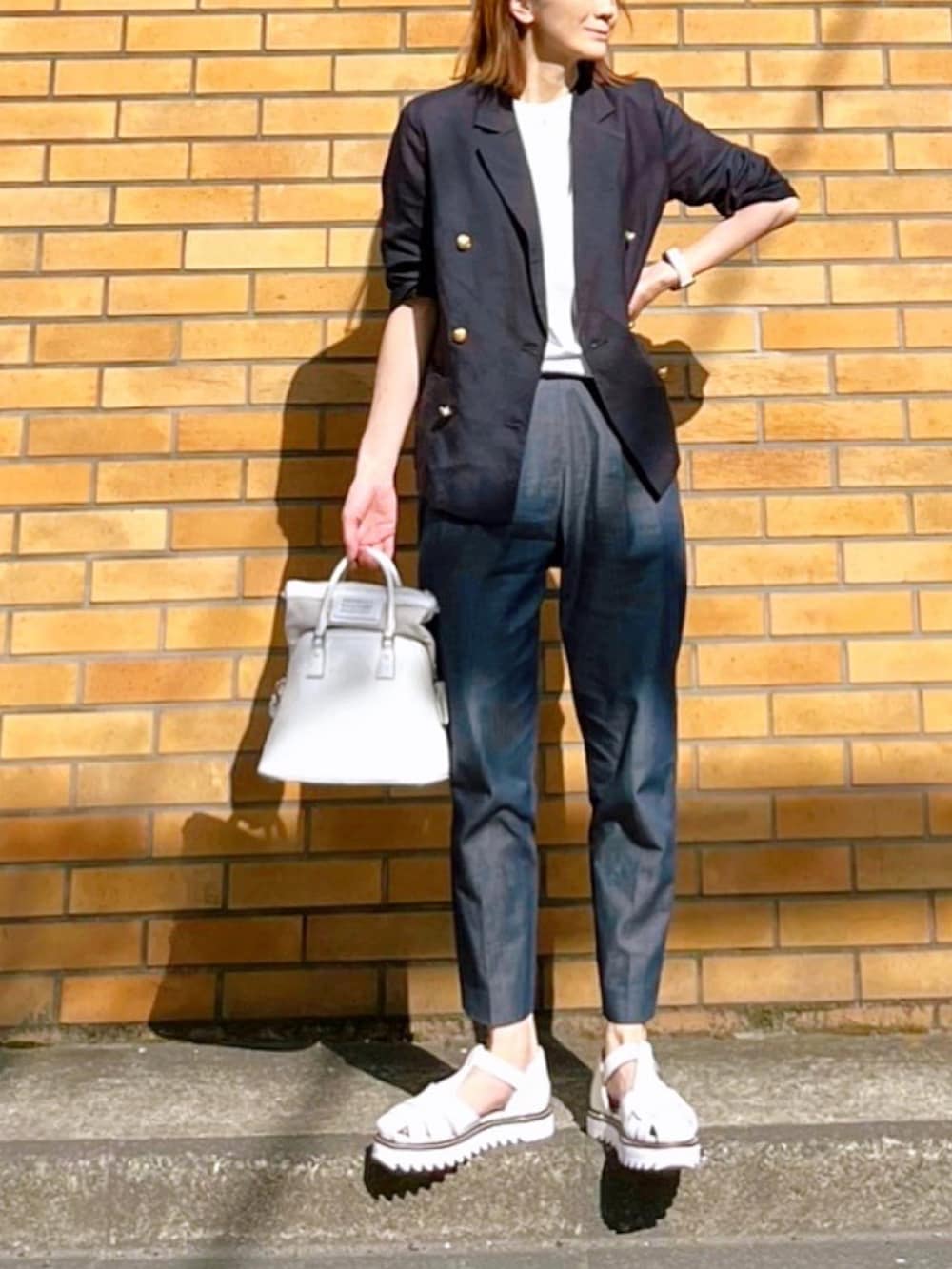 ホワイト系のハンドバッグ、ブルー系のテーラードジャケット、ブルー系のその他パンツを着用したレディースの春コーディネートの3枚目の写真