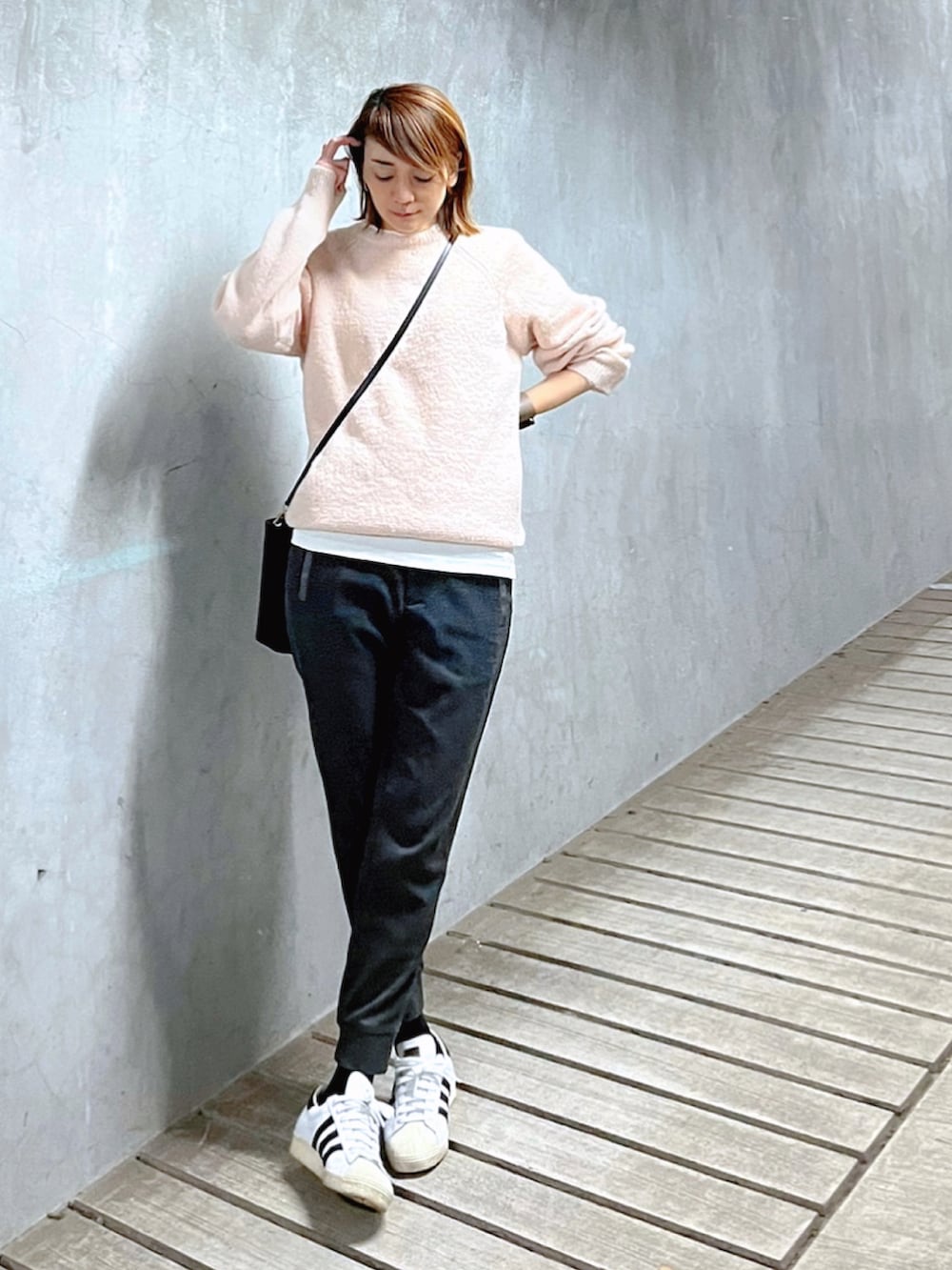 ピンク系のニット/セーター、ブラック系のトートバッグ、ホワイト系のスニーカーを着用したレディースの冬コーディネートの3枚目の写真