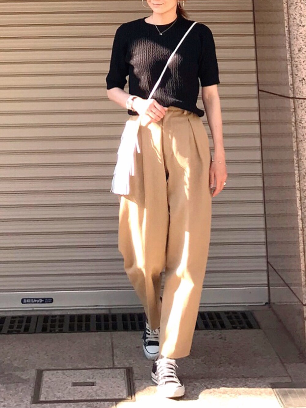 ブラック系のニット/セーター、ベージュ系のその他パンツ、ホワイト系のショルダーバッグを着用したレディースの春コーディネートの2枚目の写真