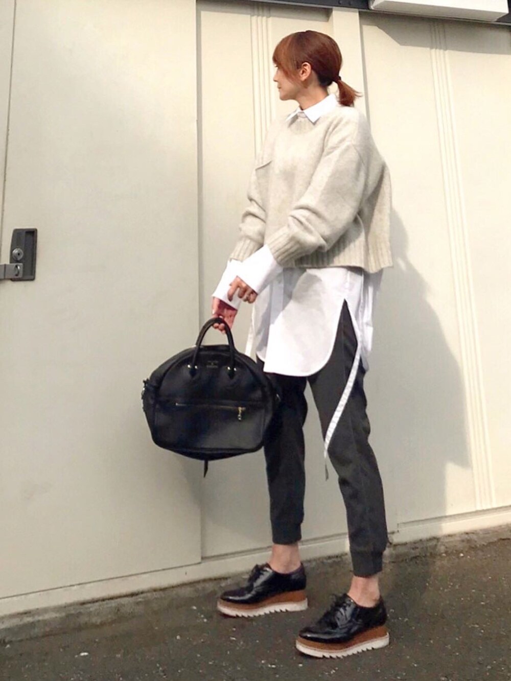 ホワイト系のシャツ/ブラウス、グレー系のニット/セーター、ブラック系のドレスシューズを着用したレディースの春コーディネートの3枚目の写真