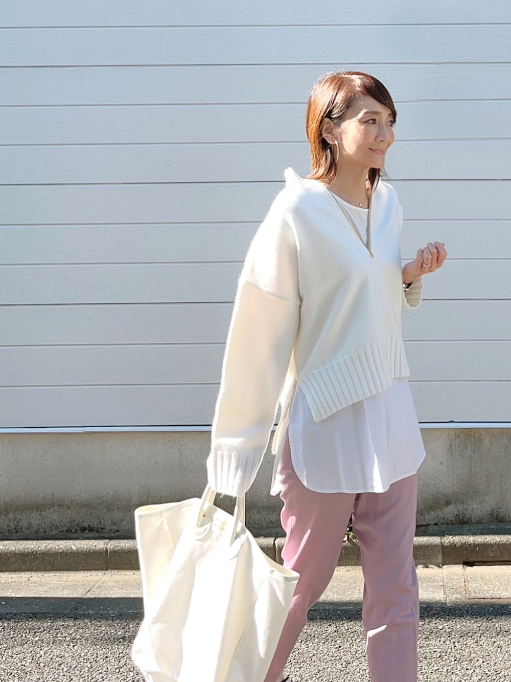 ホワイト系のニット/セーター、ホワイト系のスニーカー、ホワイト系のトートバッグを着用したレディースの秋コーディネートの2枚目の写真