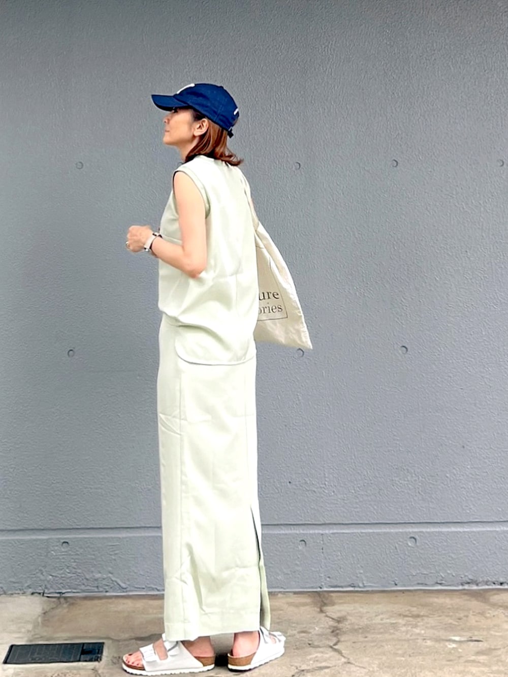 ホワイト系のサンダル、グリーン系のタンクトップ、グリーン系のスカートを着用したレディースの夏コーディネートの2枚目の写真