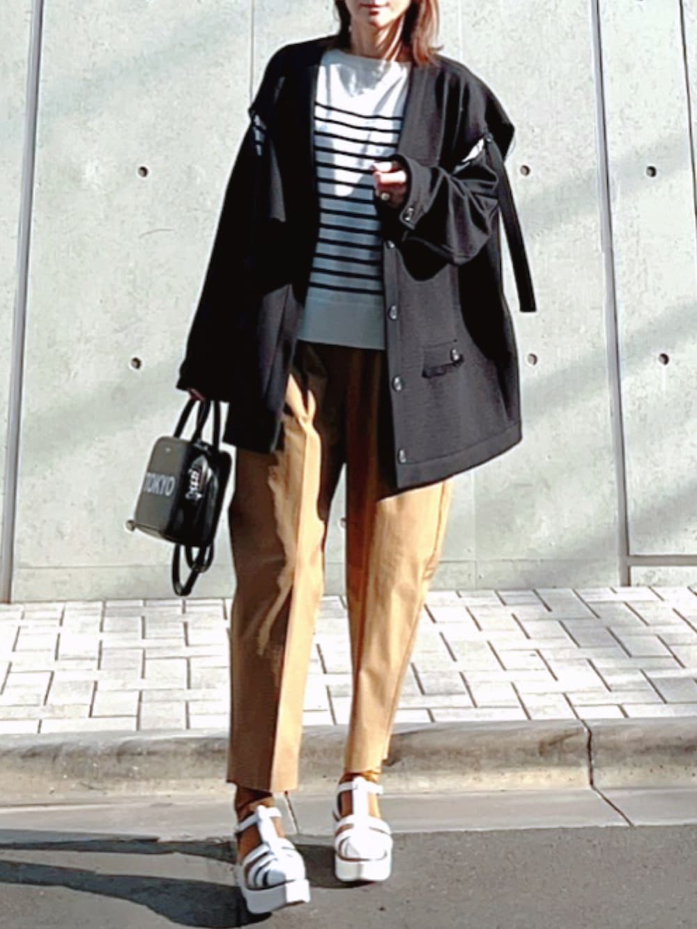 ホワイト系のニット/セーター、ブラック系のノーカラージャケット、ホワイト系のサンダルを着用したレディースの秋コーディネートの2枚目の写真