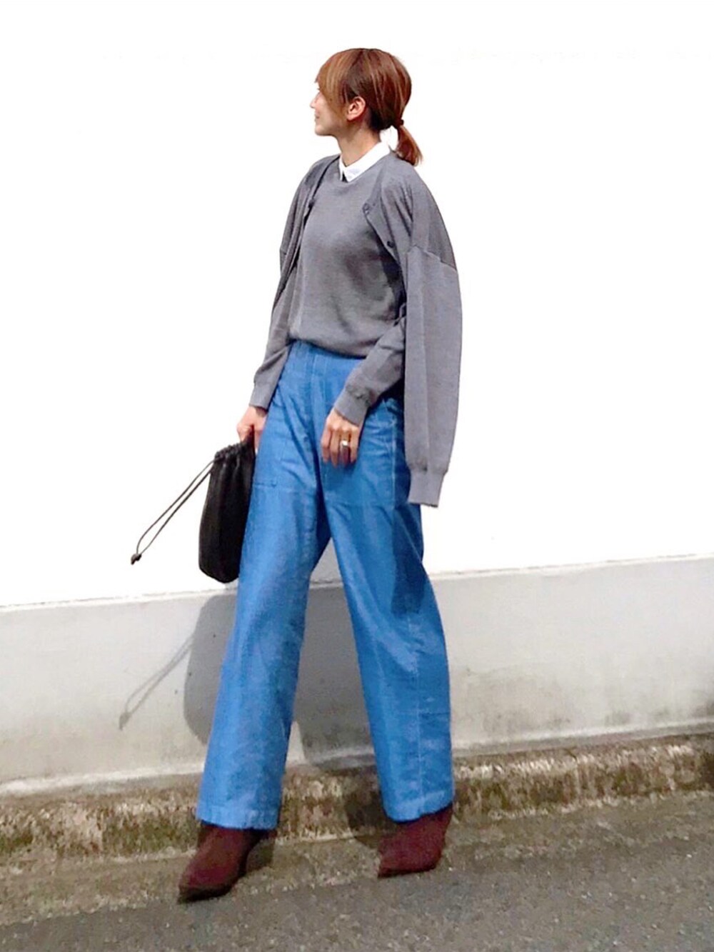 グレー系のニット/セーター、ブラウン系のハンドバッグ、ブルー系のその他パンツを着用したレディースの春コーディネートの2枚目の写真