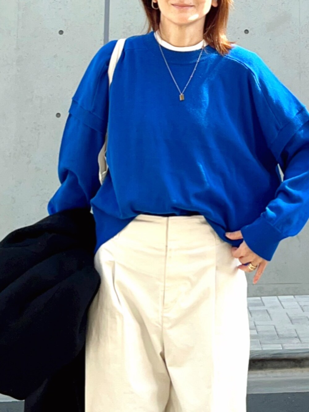 ブルー系のニット/セーター、ホワイト系のその他パンツ、ホワイト系のスニーカーを着用したレディースの春コーディネートの2枚目の写真