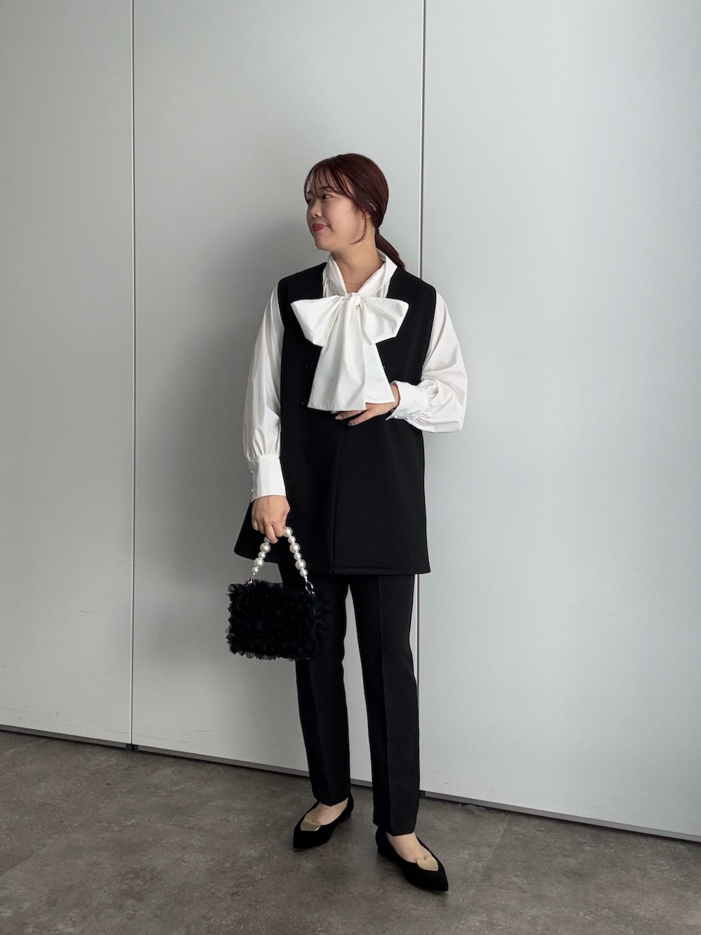 ベージュ系のトレンチコート、ホワイト系のシャツ/ブラウス、ブラック系のベストを着用したレディースの冬コーディネートの2枚目の写真