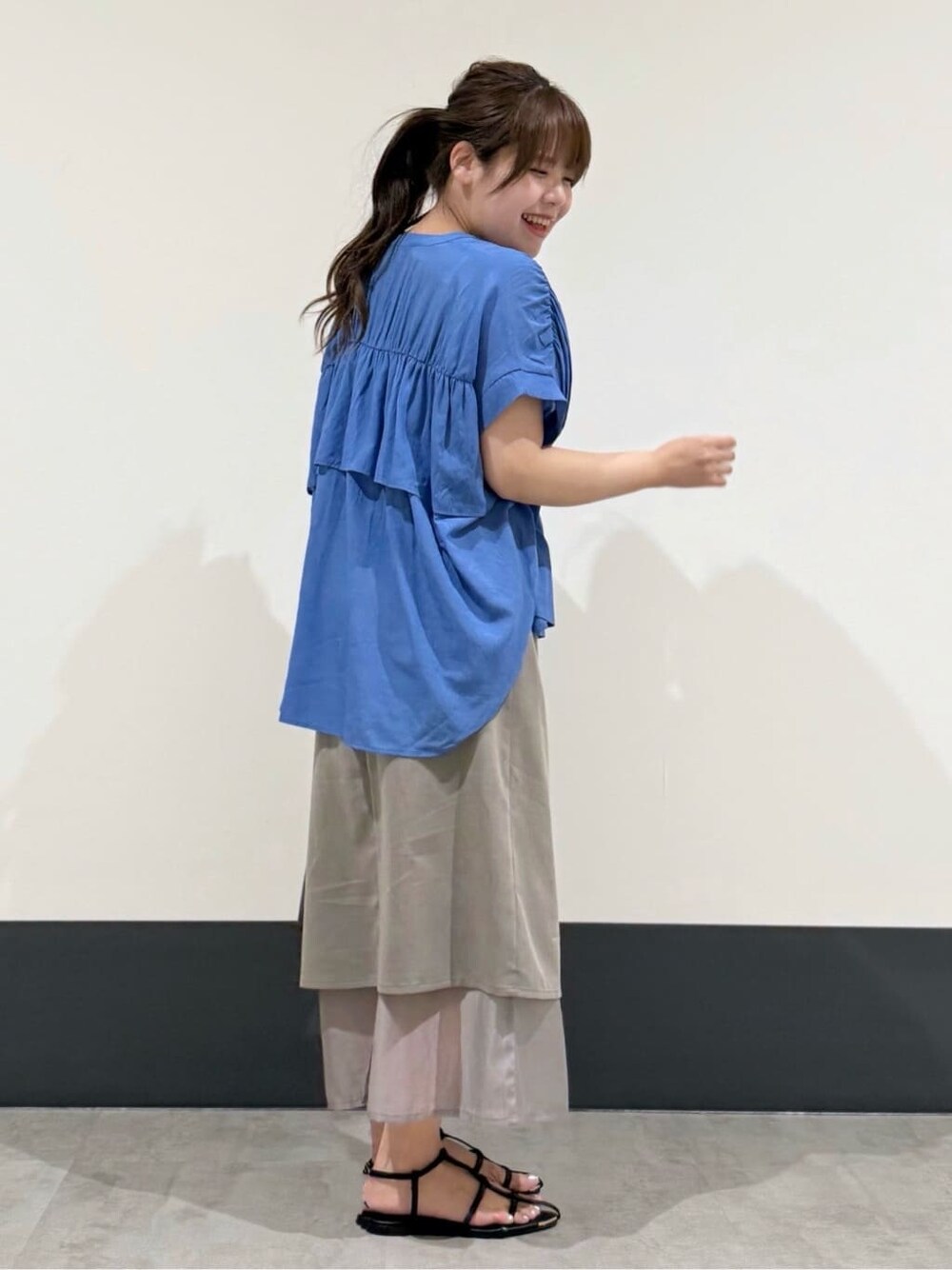 ブルー系のシャツ/ブラウス、グレー系のスカート、ブラック系のショルダーバッグを着用したレディースの夏コーディネートの3枚目の写真