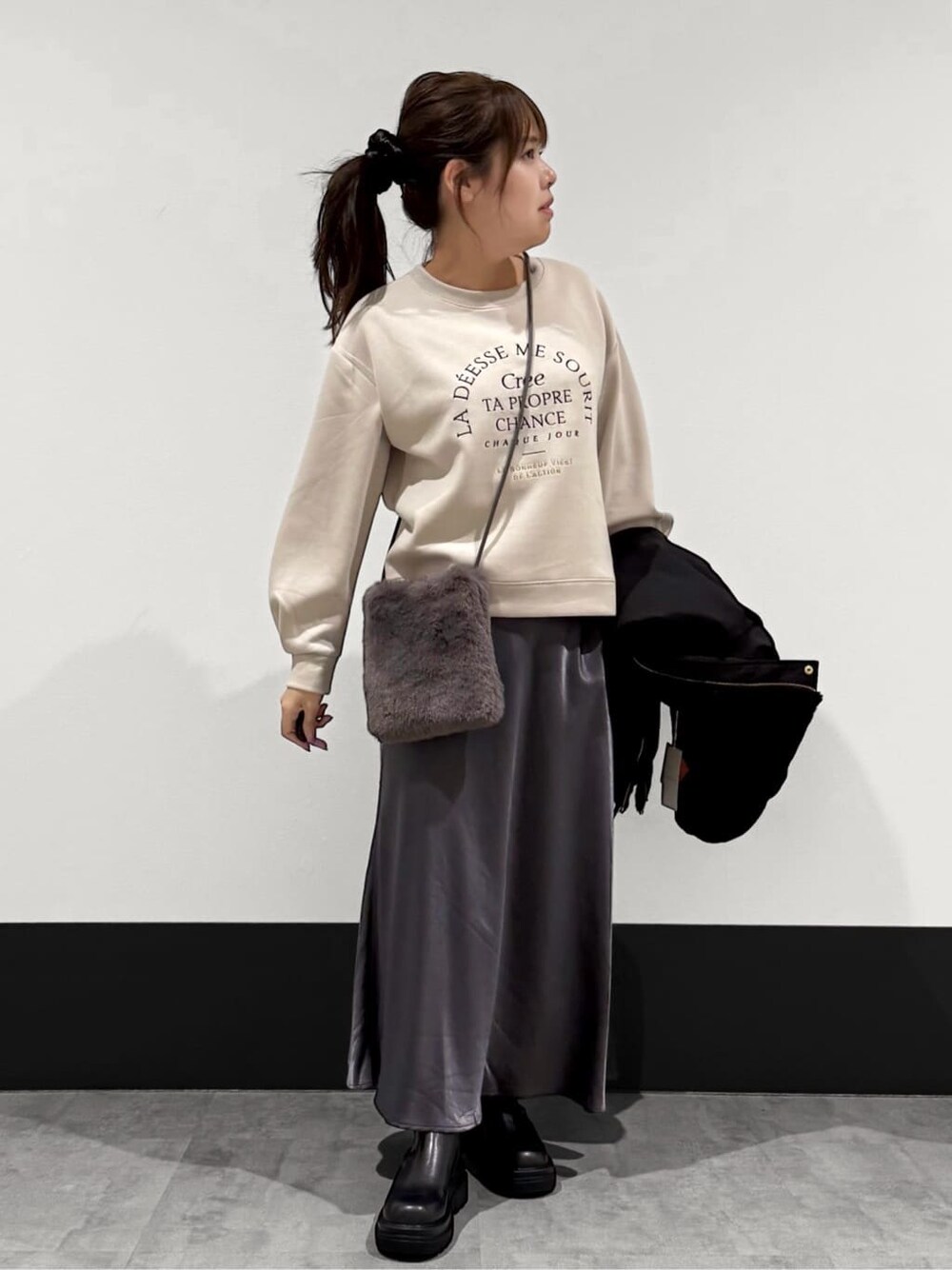 ブラック系のブルゾン、ベージュ系のTシャツ/カットソー、ブラック系のスカートを着用したレディースの秋コーディネートの3枚目の写真