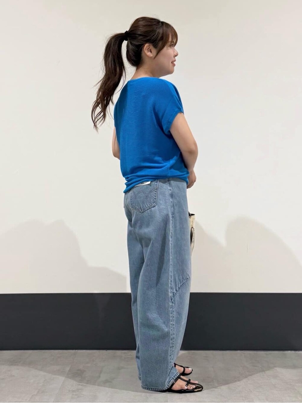 ブルー系のニット/セーター、ブラック系のショルダーバッグ、ブラック系のサンダルを着用したレディースの夏コーディネートの3枚目の写真