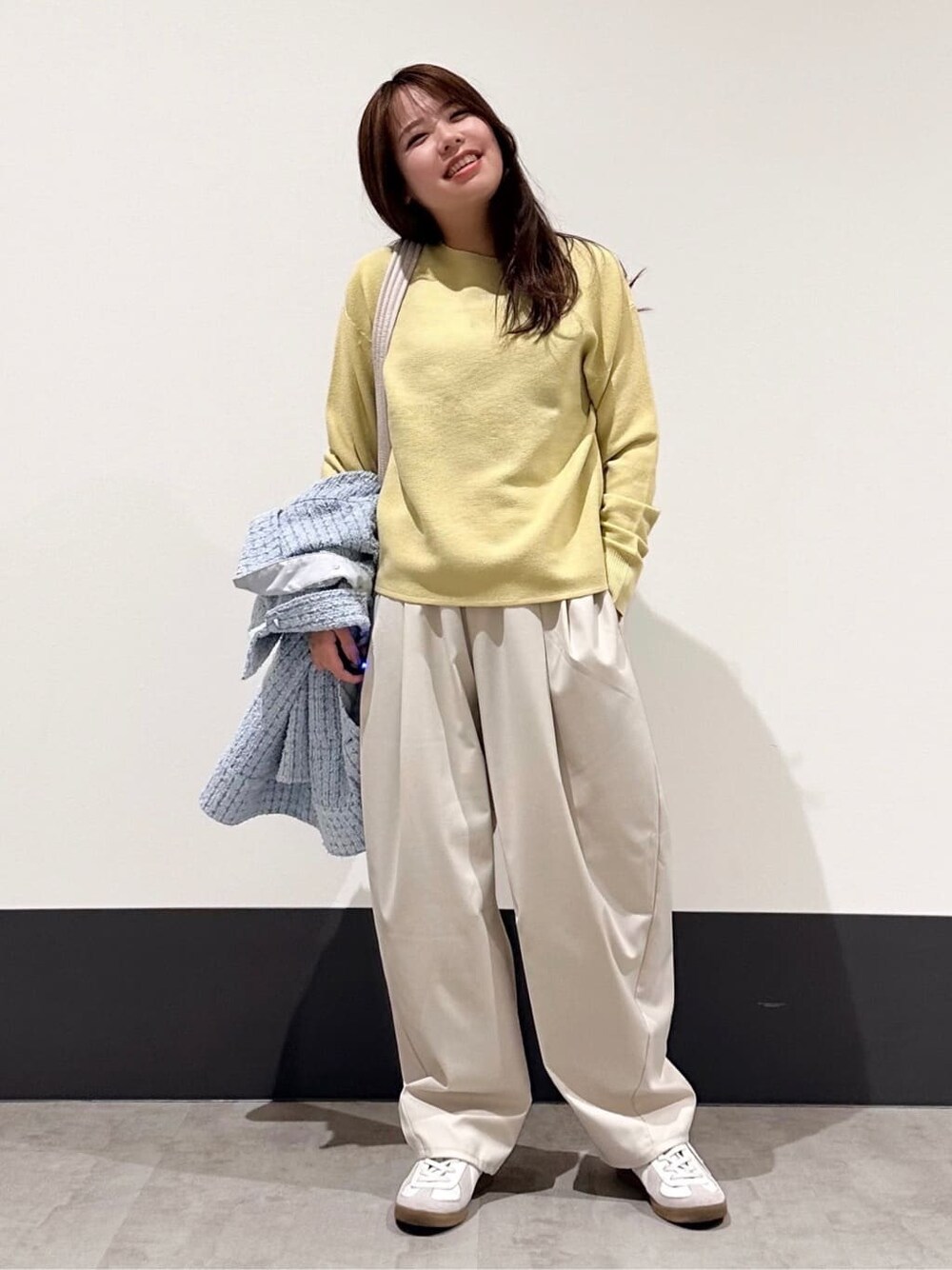 ブルー系のデニムジャケット、イエロー系のニット/セーター、ベージュ系のその他パンツを着用したレディースの春コーディネートの4枚目の写真