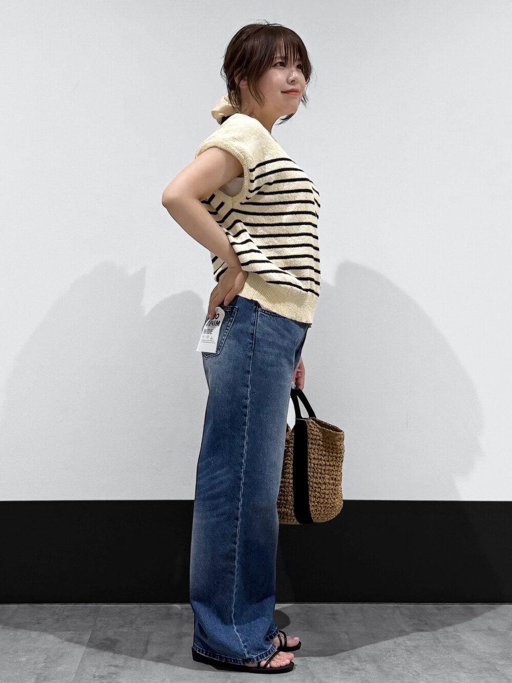 ベージュ系のニット/セーター、ブルー系のデニムパンツ、ブラック系のトートバッグを着用したレディースの春コーディネートの3枚目の写真