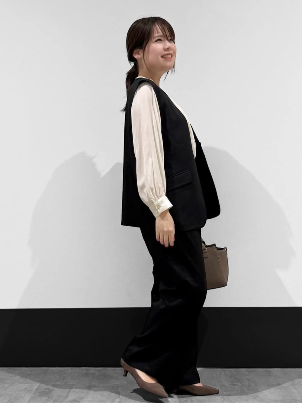 ブラック系のベスト、ホワイト系のシャツ/ブラウス、ブラック系のその他パンツを着用したレディースの春コーディネートの2枚目の写真