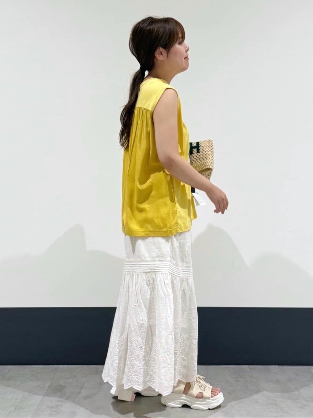 イエロー系のTシャツ/カットソー、ホワイト系のスカート、ホワイト系のトートバッグを着用したレディースの夏コーディネートの2枚目の写真