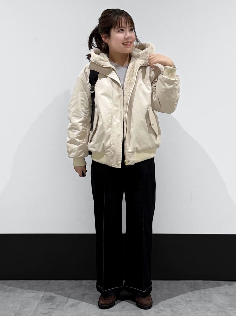 ベージュ系のブルゾン、グレー系のニット/セーター、ブラック系のデニムパンツを着用したレディースの冬コーディネートの2枚目の写真