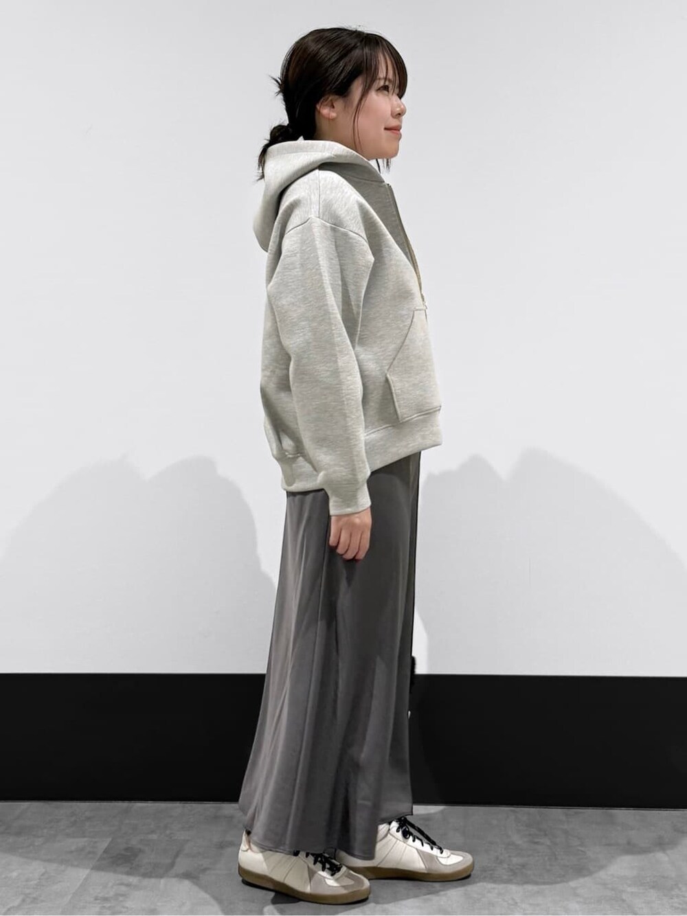 グレー系のカーディガン/ボレロ、ホワイト系のTシャツ/カットソー、ブラック系のスカートを着用したレディースの春コーディネートの2枚目の写真