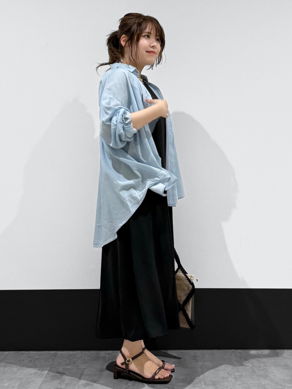 ブルー系のシャツ/ブラウス、ブラック系のワンピース、ブラック系のトートバッグを着用したレディースの夏コーディネートの2枚目の写真