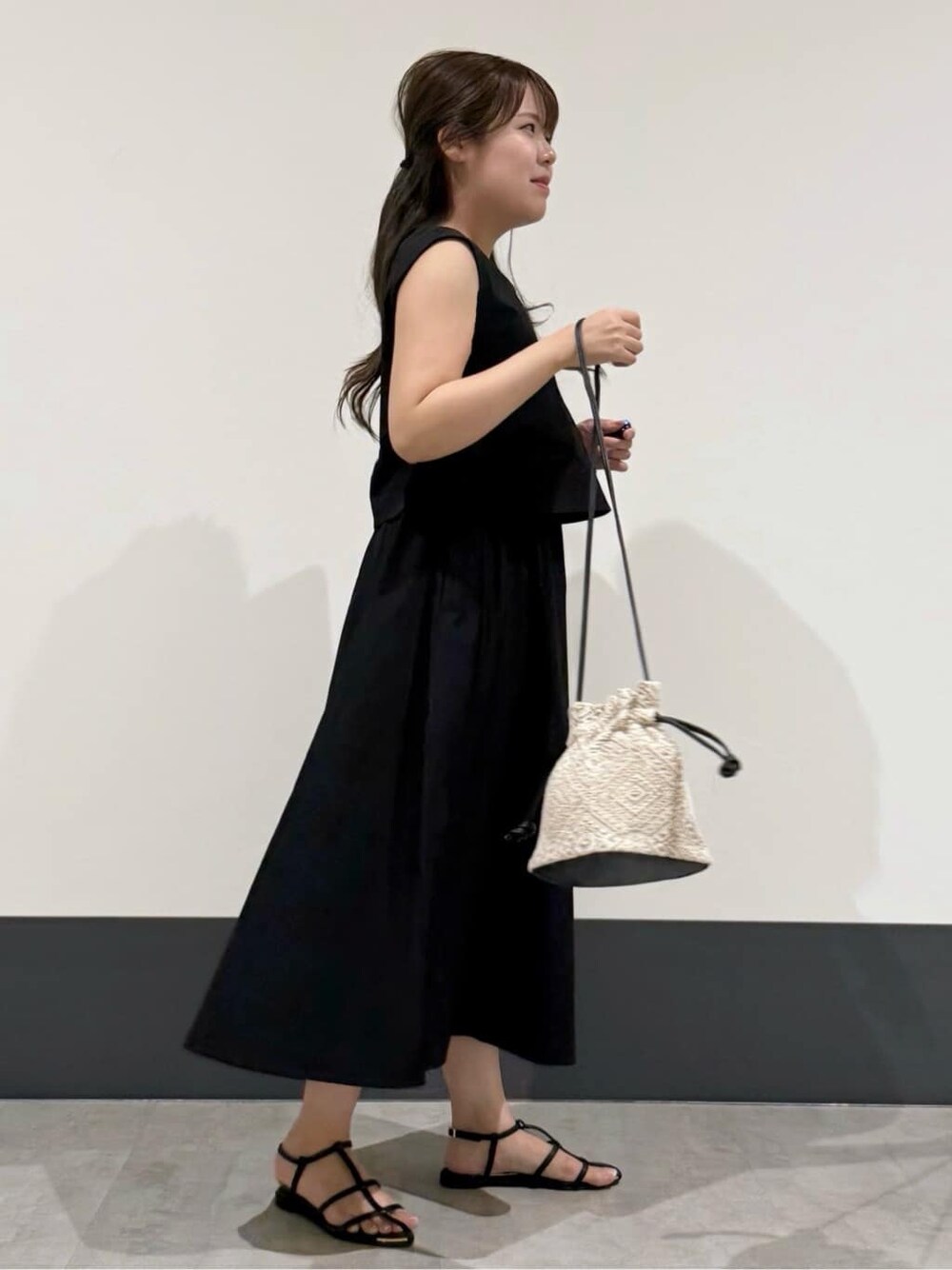 ブラック系のワンピース、ブラック系のショルダーバッグ、ブラック系のサンダルを着用したレディースの夏コーディネートの3枚目の写真
