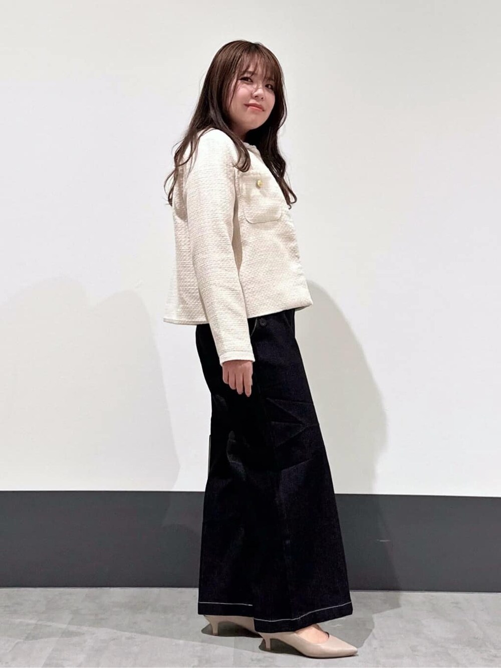 ベージュ系のノーカラージャケット、ピンク系のニット/セーター、ブラック系のデニムパンツを着用したレディースの春コーディネートの2枚目の写真