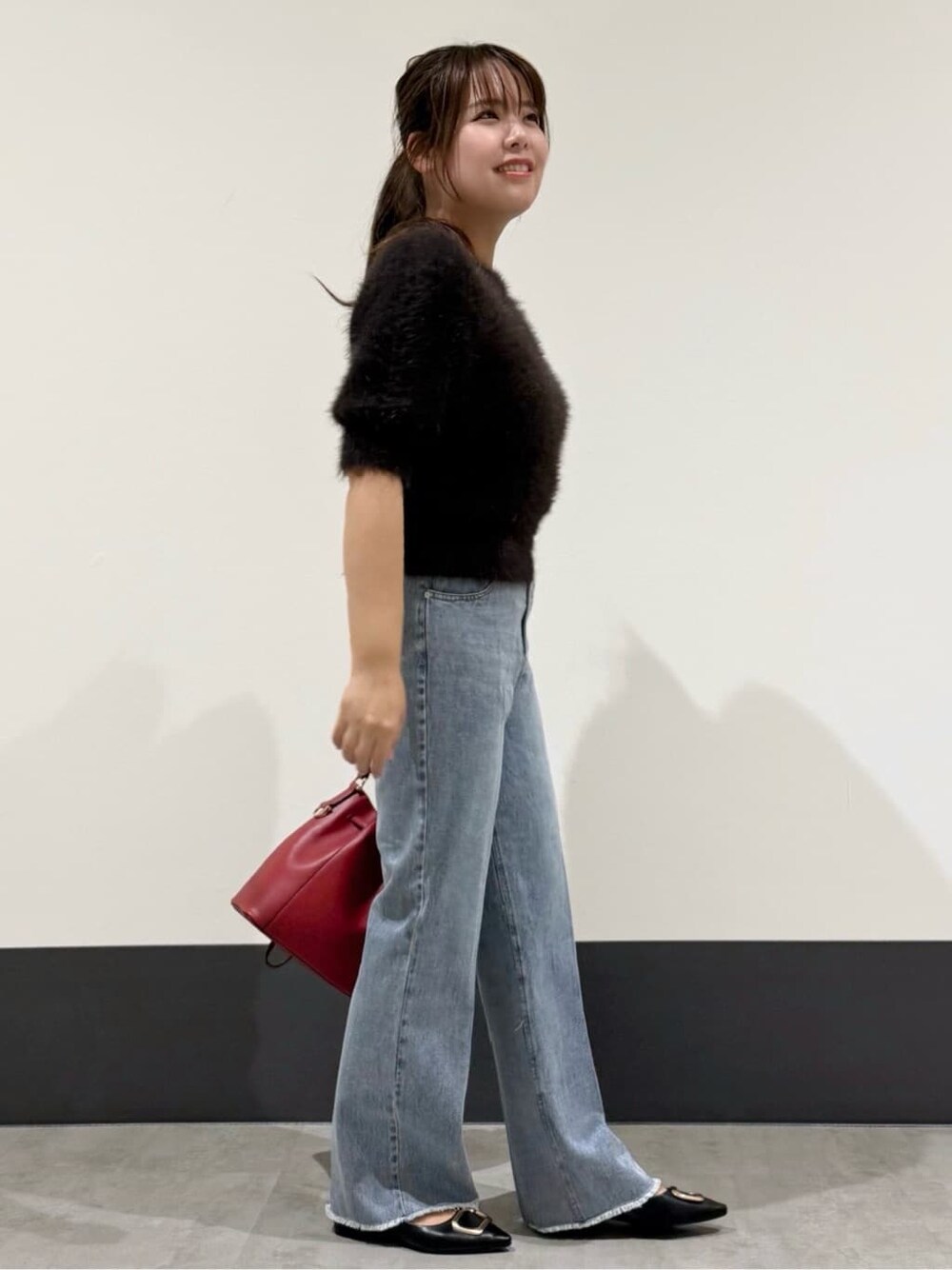 ブラウン系のニット/セーター、ブルー系のデニムパンツ、レッド系のショルダーバッグを着用したレディースの秋コーディネートの2枚目の写真