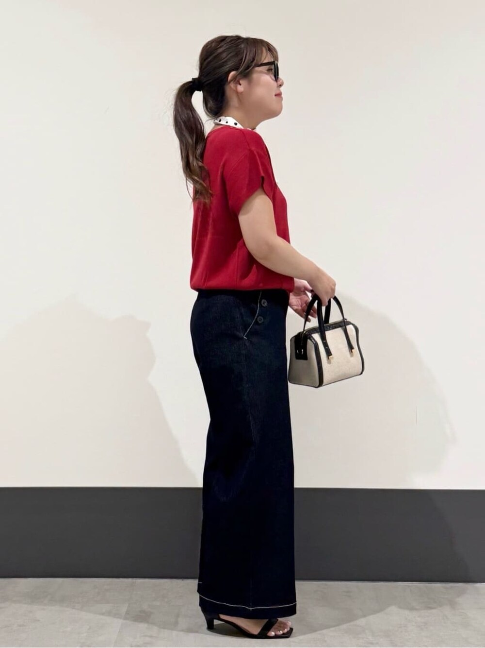 レッド系のニット/セーター、ブルー系のデニムパンツ、ブラック系のショルダーバッグを着用したレディースの夏コーディネートの2枚目の写真