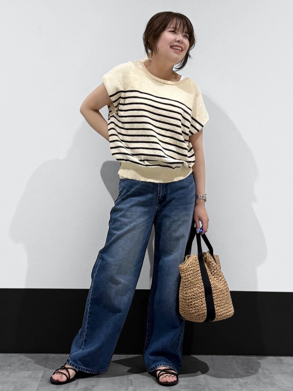 ベージュ系のニット/セーター、ブルー系のデニムパンツ、ブラック系のトートバッグを着用したレディースの春コーディネートの2枚目の写真