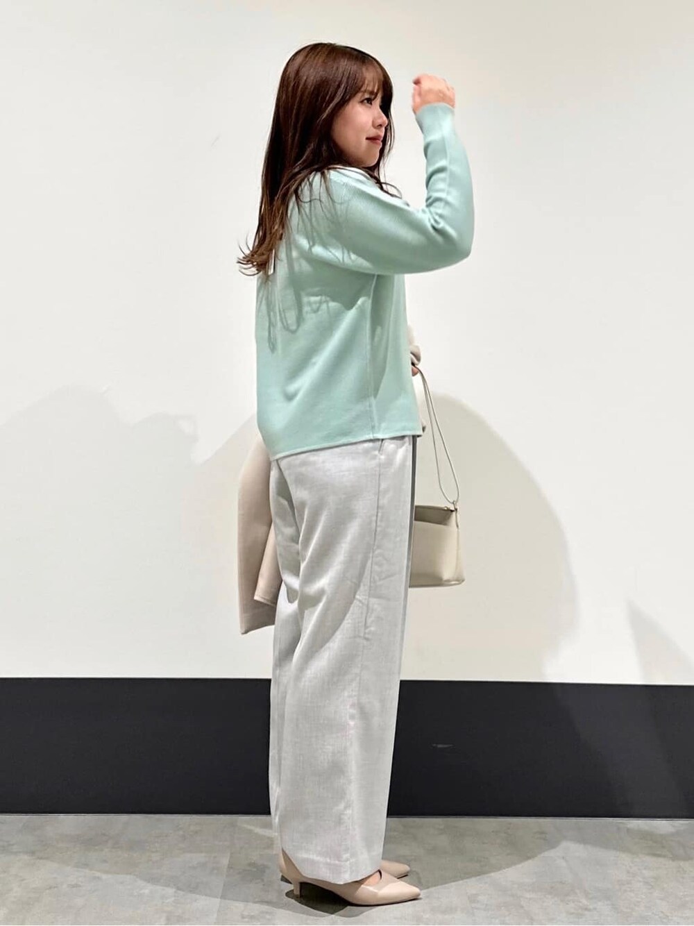 グリーン系のニット/セーター、ホワイト系のショルダーバッグ、ベージュ系のパンプスを着用したレディースの冬コーディネートの5枚目の写真