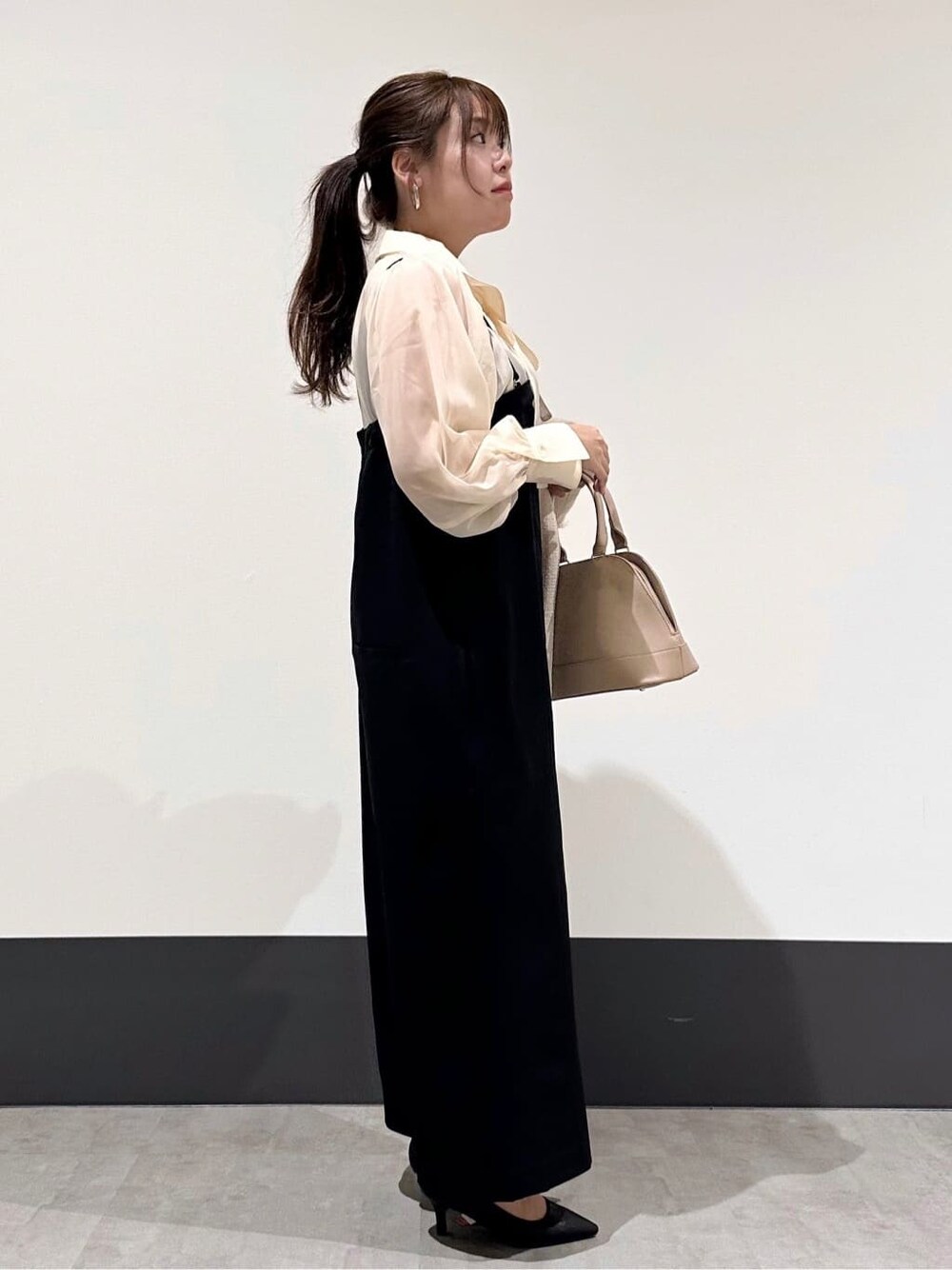 ベージュ系のノーカラージャケット、ホワイト系のシャツ/ブラウス、ブラック系のサロペット/オーバーオールを着用したレディースの冬コーディネートの4枚目の写真