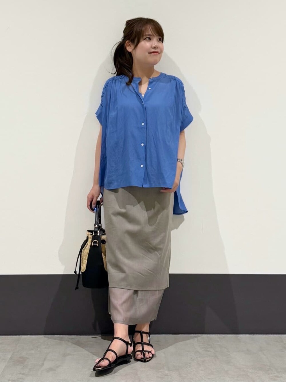 ブルー系のシャツ/ブラウス、グレー系のスカート、ブラック系のショルダーバッグを着用したレディースの夏コーディネートの2枚目の写真