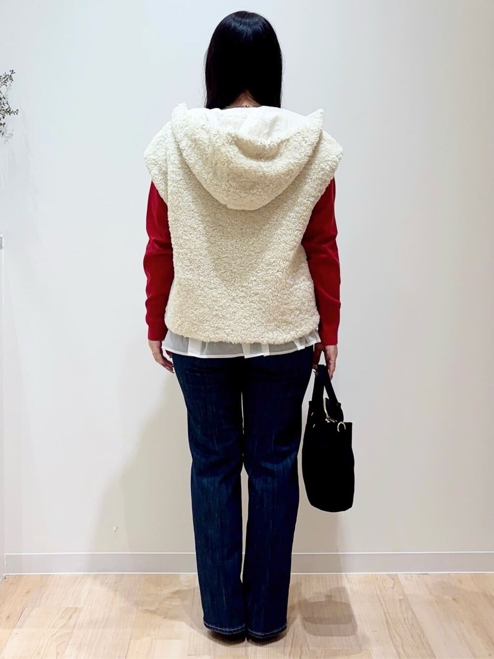 ホワイト系のブルゾン、レッド系のニット/セーター、ブルー系のデニムパンツを着用したレディースの秋コーディネートの3枚目の写真