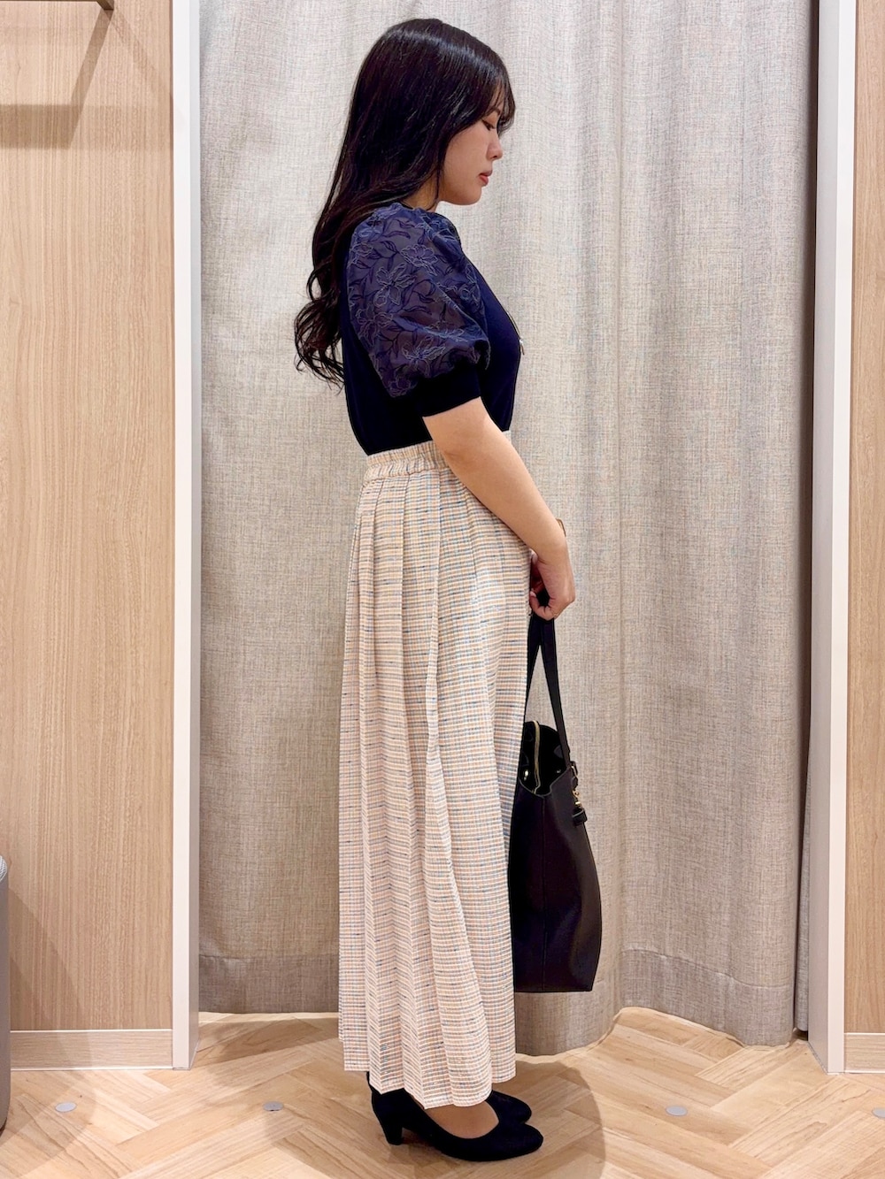 ブラック系のパンプス、ブラック系のトートバッグ、ブルー系のニット/セーターを着用したレディースの春コーディネートの2枚目の写真