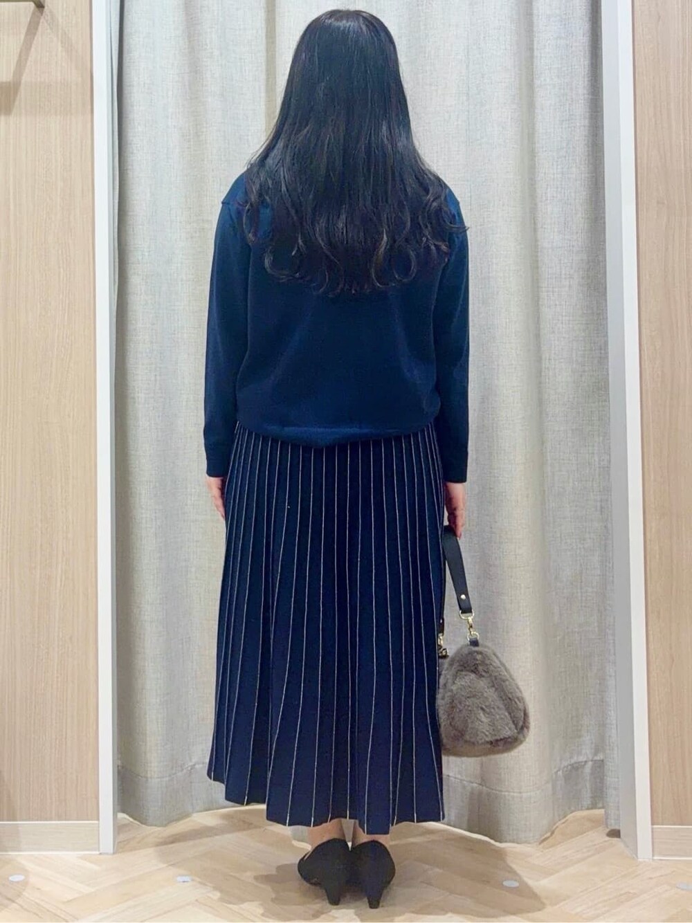 ブルー系のニット/セーター、ブルー系のスカート、グレー系のショルダーバッグを着用したレディースの冬コーディネートの3枚目の写真