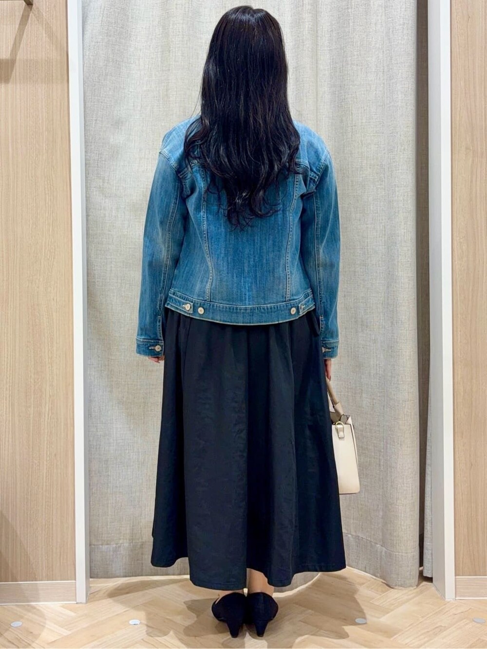 ブラック系のパンプス、ベージュ系のトートバッグ、ブルー系のデニムジャケットを着用したレディースの春コーディネートの3枚目の写真