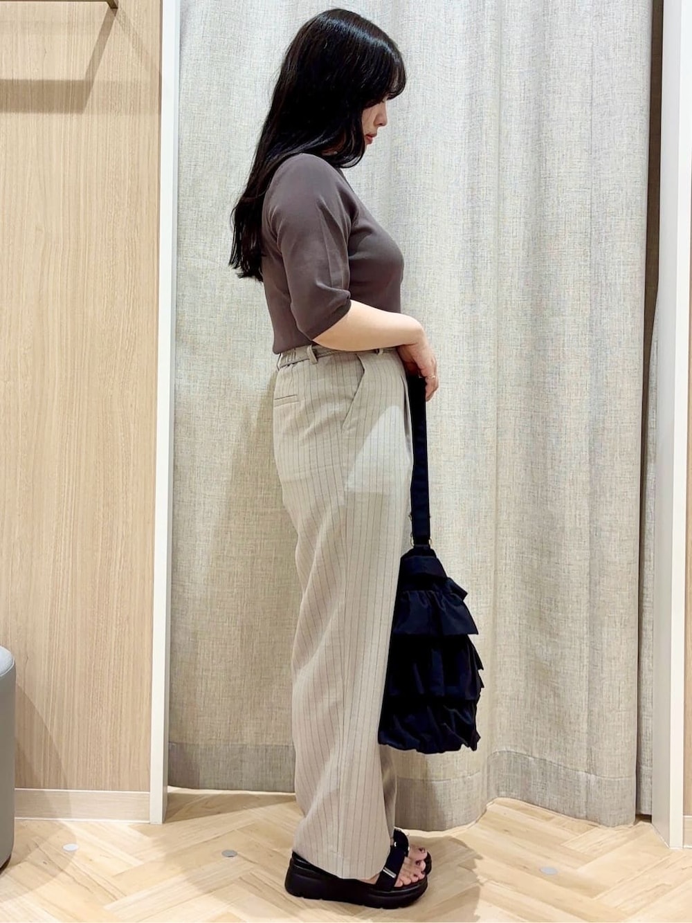 グレー系のニット/セーター、グレー系のその他パンツ、ブラック系のショルダーバッグを着用したレディースの夏コーディネートの2枚目の写真