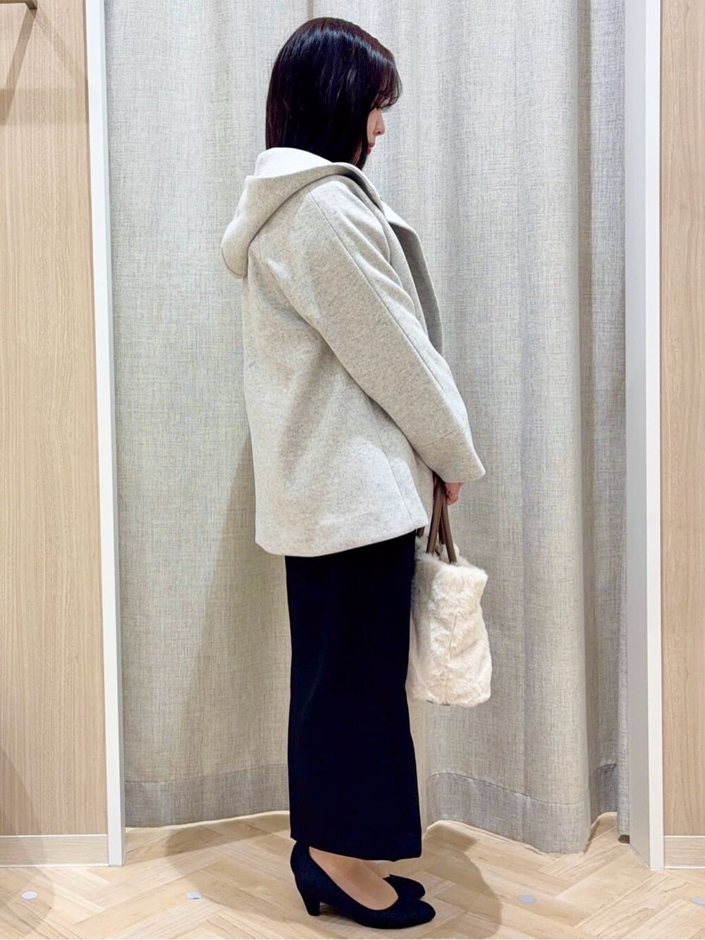 グレー系のその他アウター、ブラック系のスカート、ホワイト系のトートバッグを着用したレディースの冬コーディネートの2枚目の写真