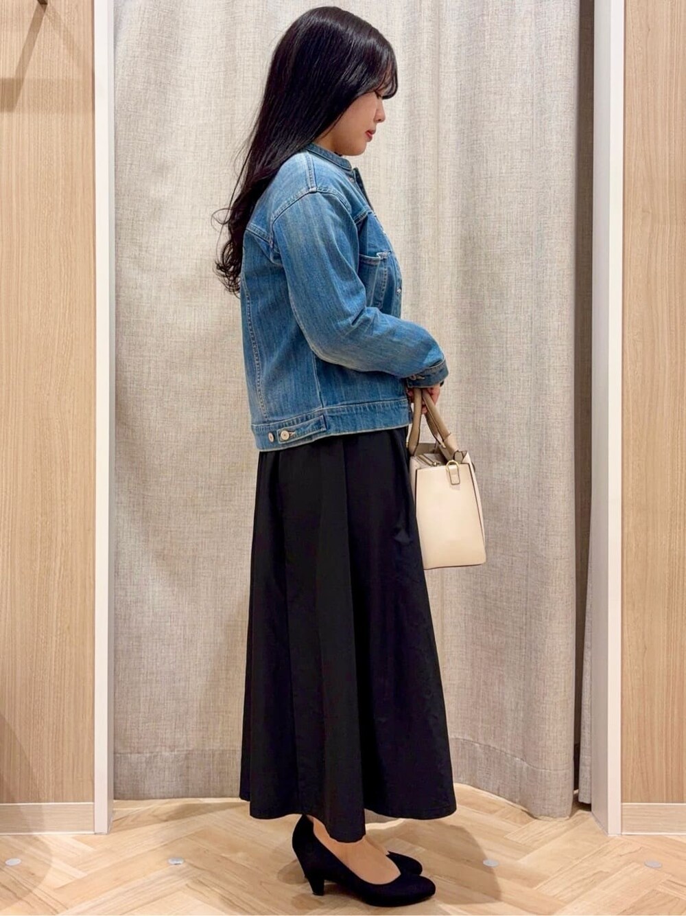 ブラック系のパンプス、ベージュ系のトートバッグ、ブルー系のデニムジャケットを着用したレディースの春コーディネートの2枚目の写真